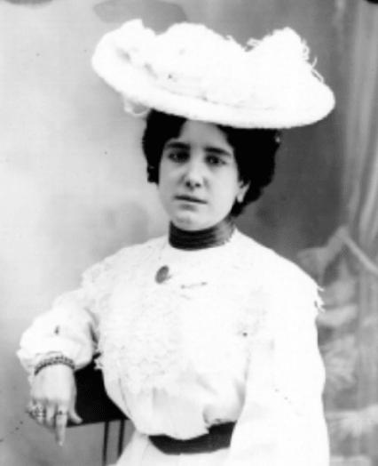 Woman with a hat sitting on a chair.