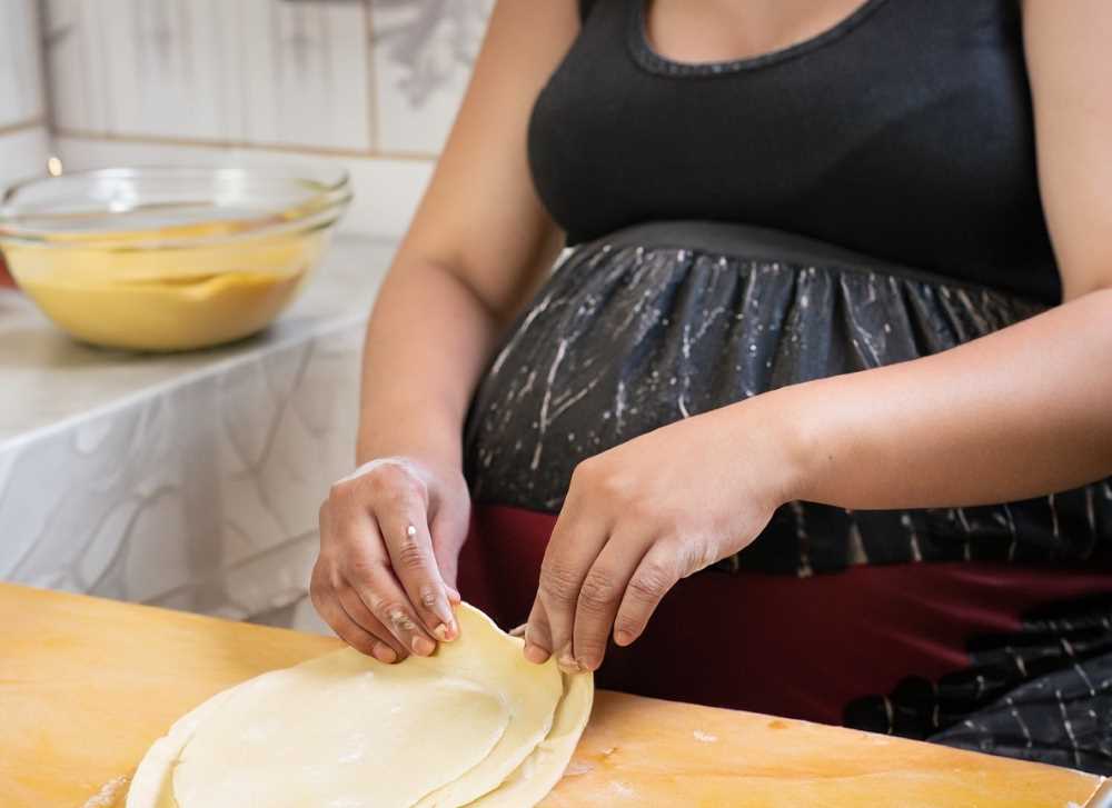 A pregnant woman preparing tamale dough, highlighting the cultural belief.