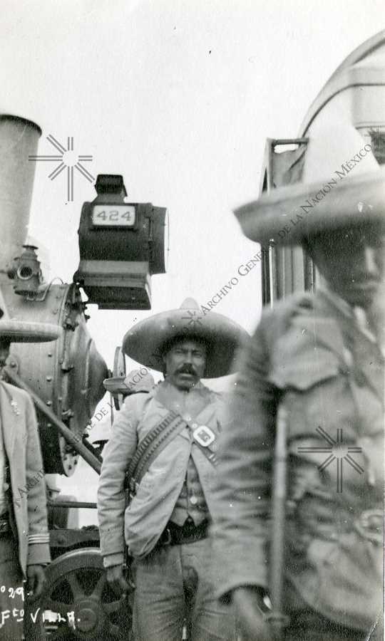 Francisco Villa standing next to a railroad engine, 1912.