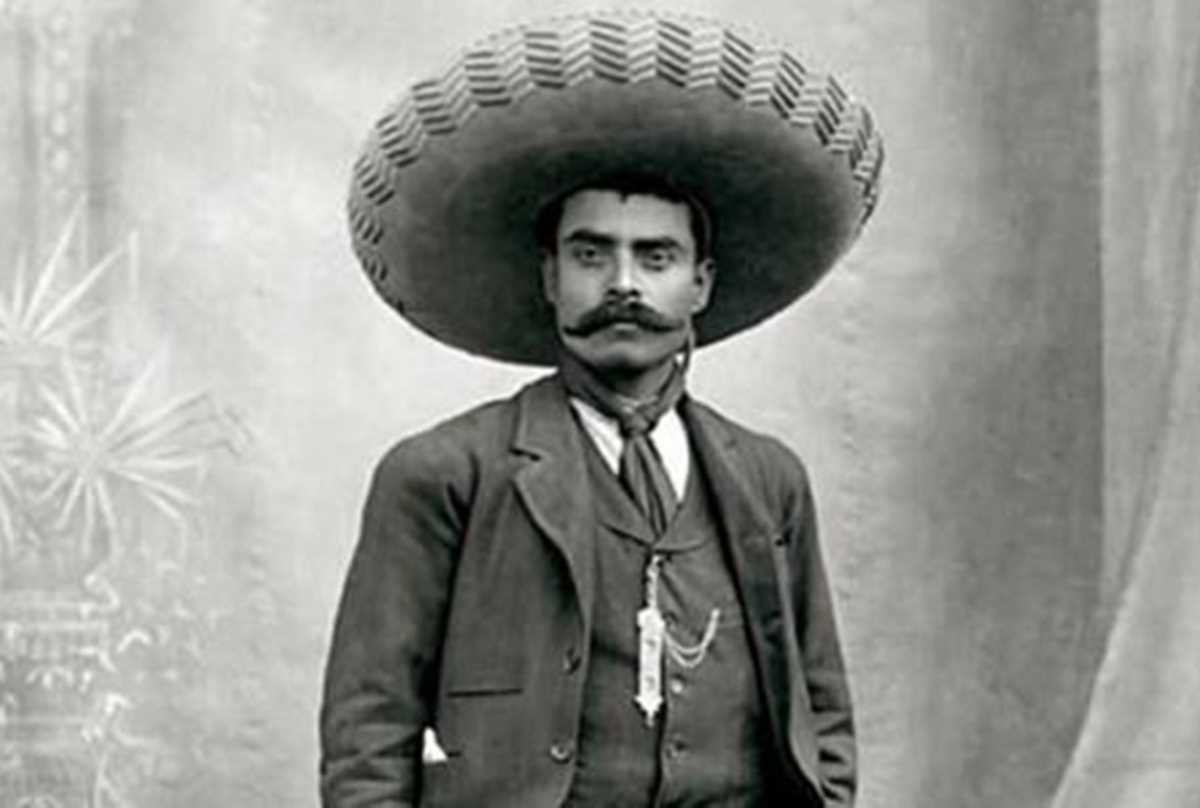 lack and white portrait of Emiliano Zapata, a Mexican revolutionary with a mustache and determined expression, wearing a sombrero and traditional clothing.