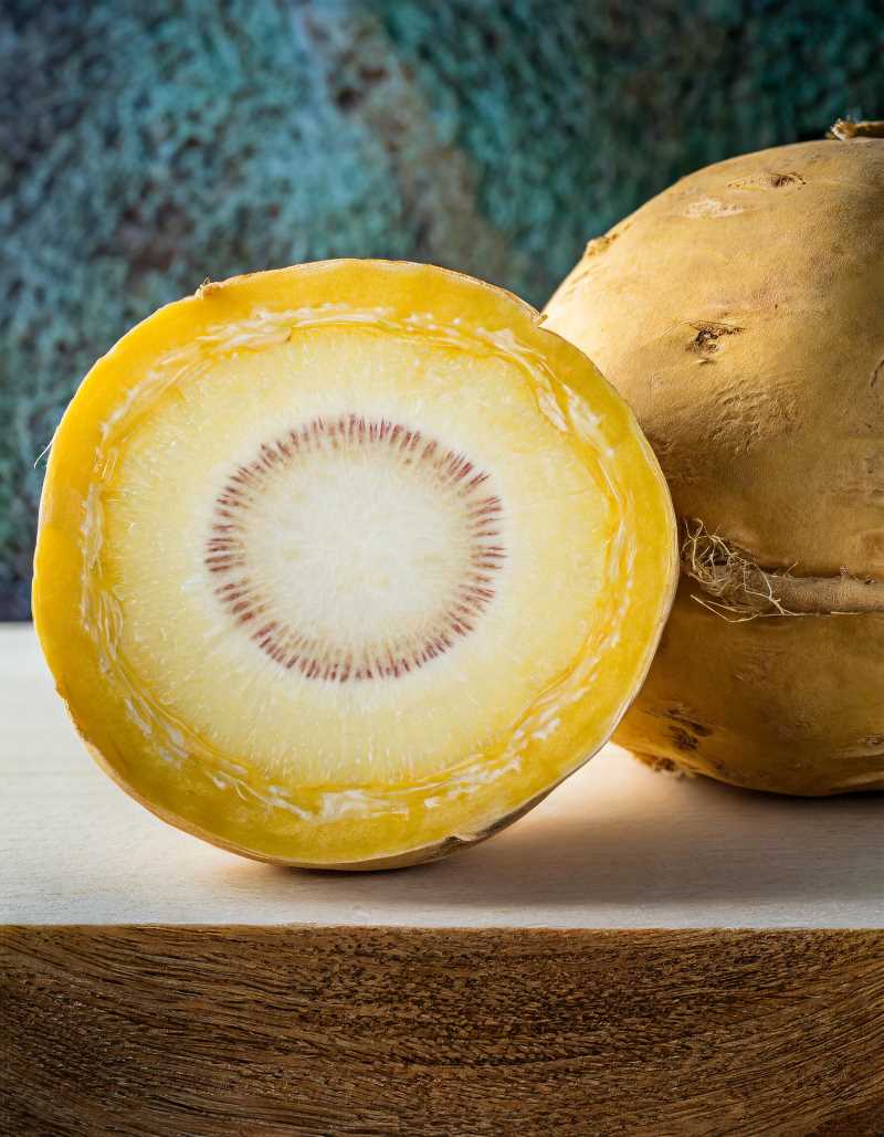 A cross-section of a rutabaga, showcasing its yellow interior and textured, yellowish skin.