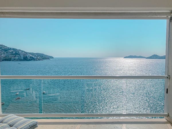 A sunny view on the Acapulco bay through an open window and a balcony.