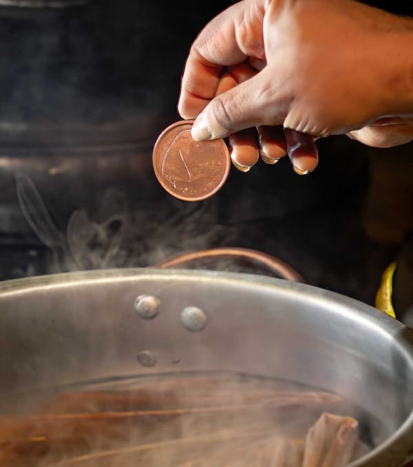 A copper coin dances in the pot, signaling that the tamales are steaming to perfection.