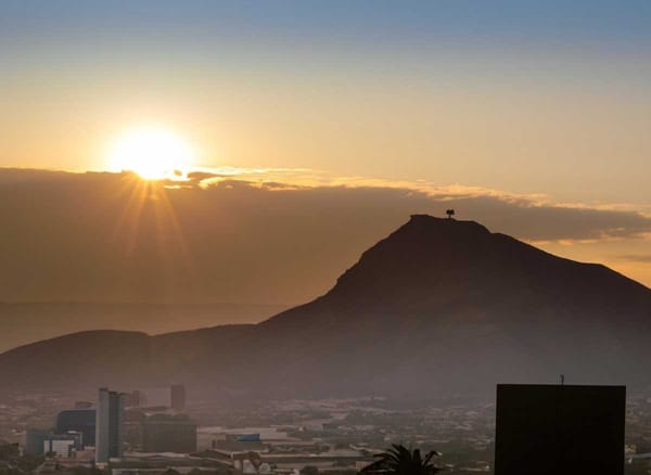 The sun sets behind Cerro de la Silla, casting a golden hue over Monterrey's iconic Great Plaza.