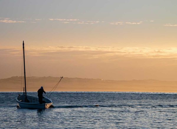 A lone fisherman in Bahía de Los Ángeles sets sail at dawn, embodying the traditional livelihoods.