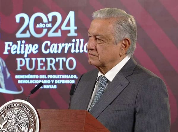 President Andrés Manuel López Obrador stands at a podium addressing a crowd in the National Palace.