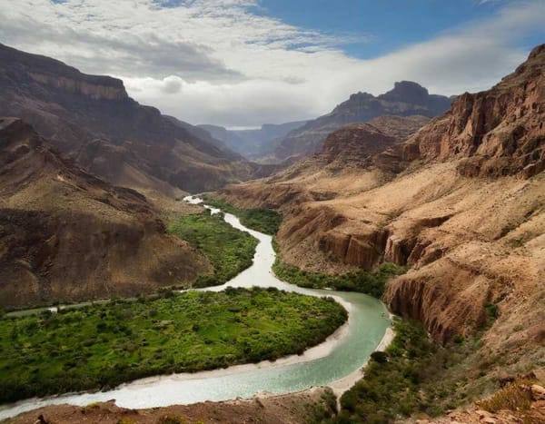 Green valley with a river surrounded by brown mountains in a desert landscape.