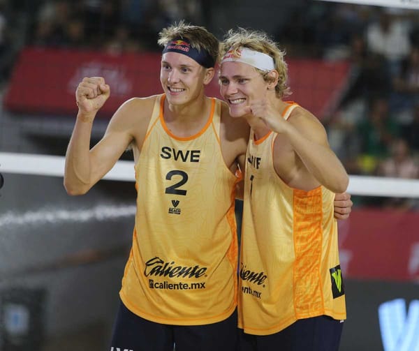 Två svenska beachvolleybollspelare, Åhman och Hellvig, gör high five i triumf.