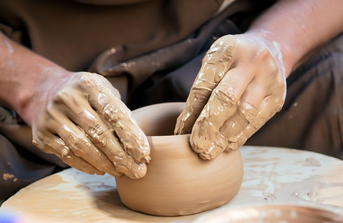 An artisan's hands skillfully shape clay, connecting past and present.