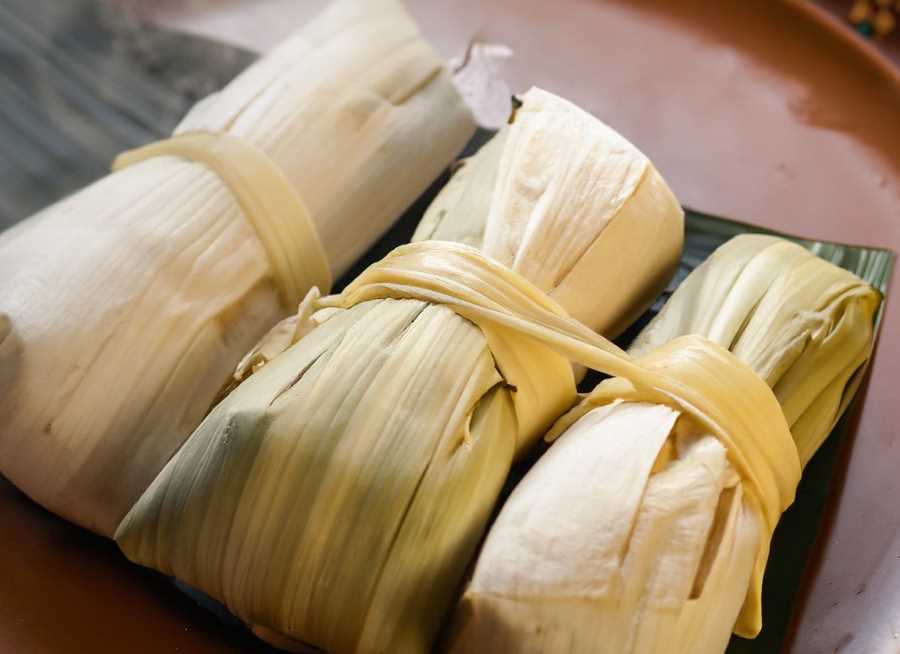 A steaming plate of freshly made rice tamales, a traditional Mexican delicacy with a rich history.