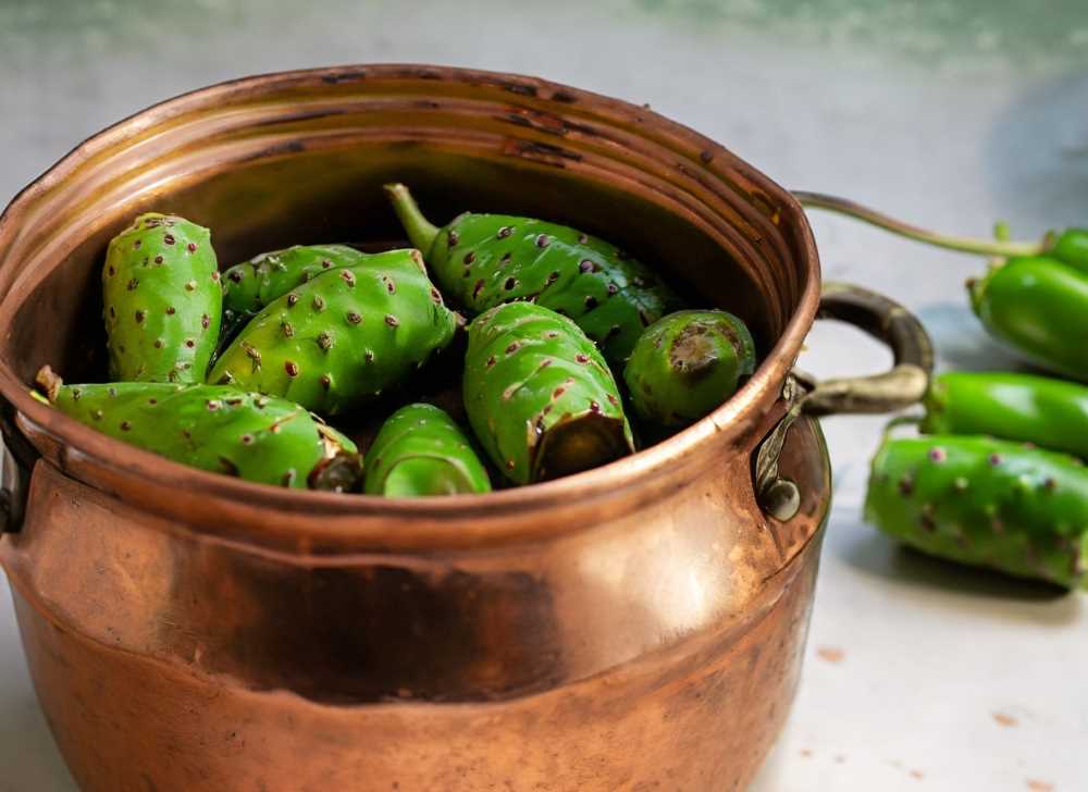 A copper pot filled with green prickly pear cactus, showcasing the color-retaining properties of cooking with copper.