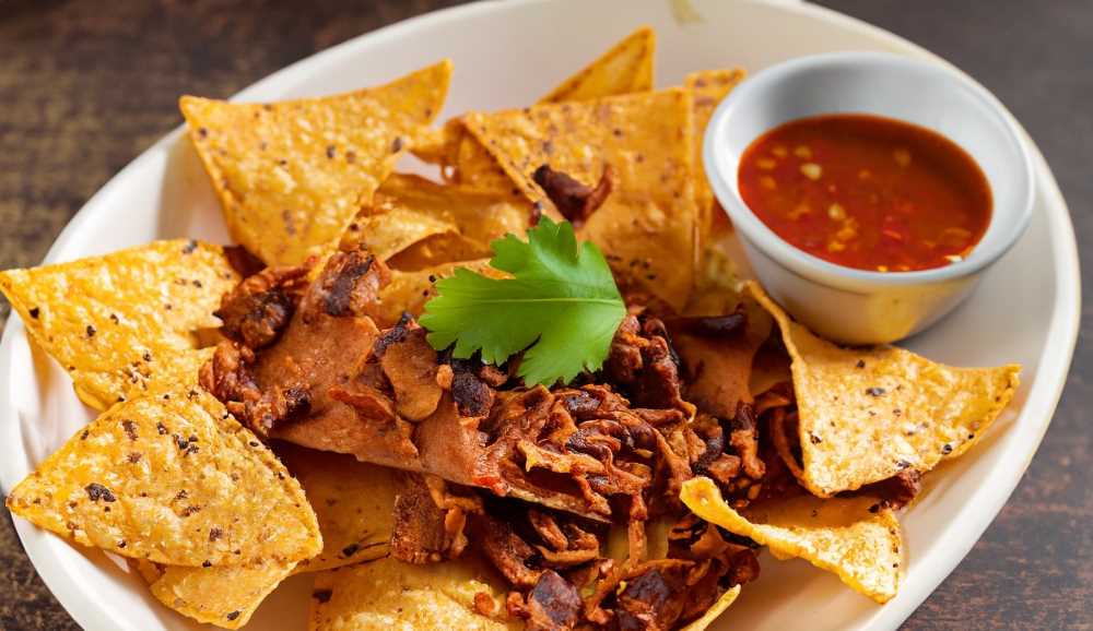 Indulge in the flavors of a savory blend of crispy tortilla chips, tender shredded pork, and spicy pasilla sauce.