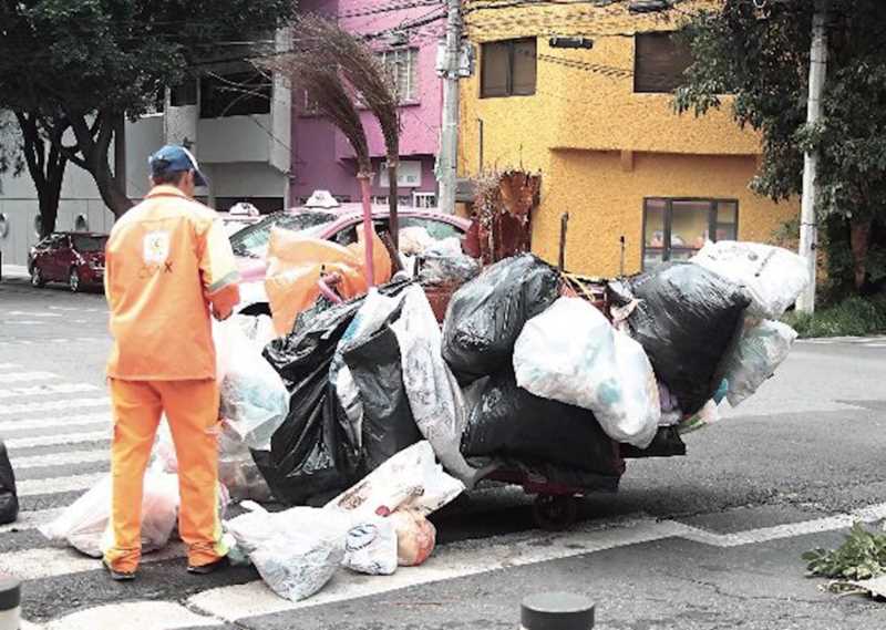 A dedicated street sweeper in Mexico City's Historic Center, working tirelessly to collect waste.